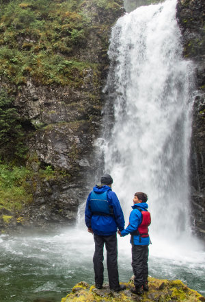 Father and son stand in front of waterfall