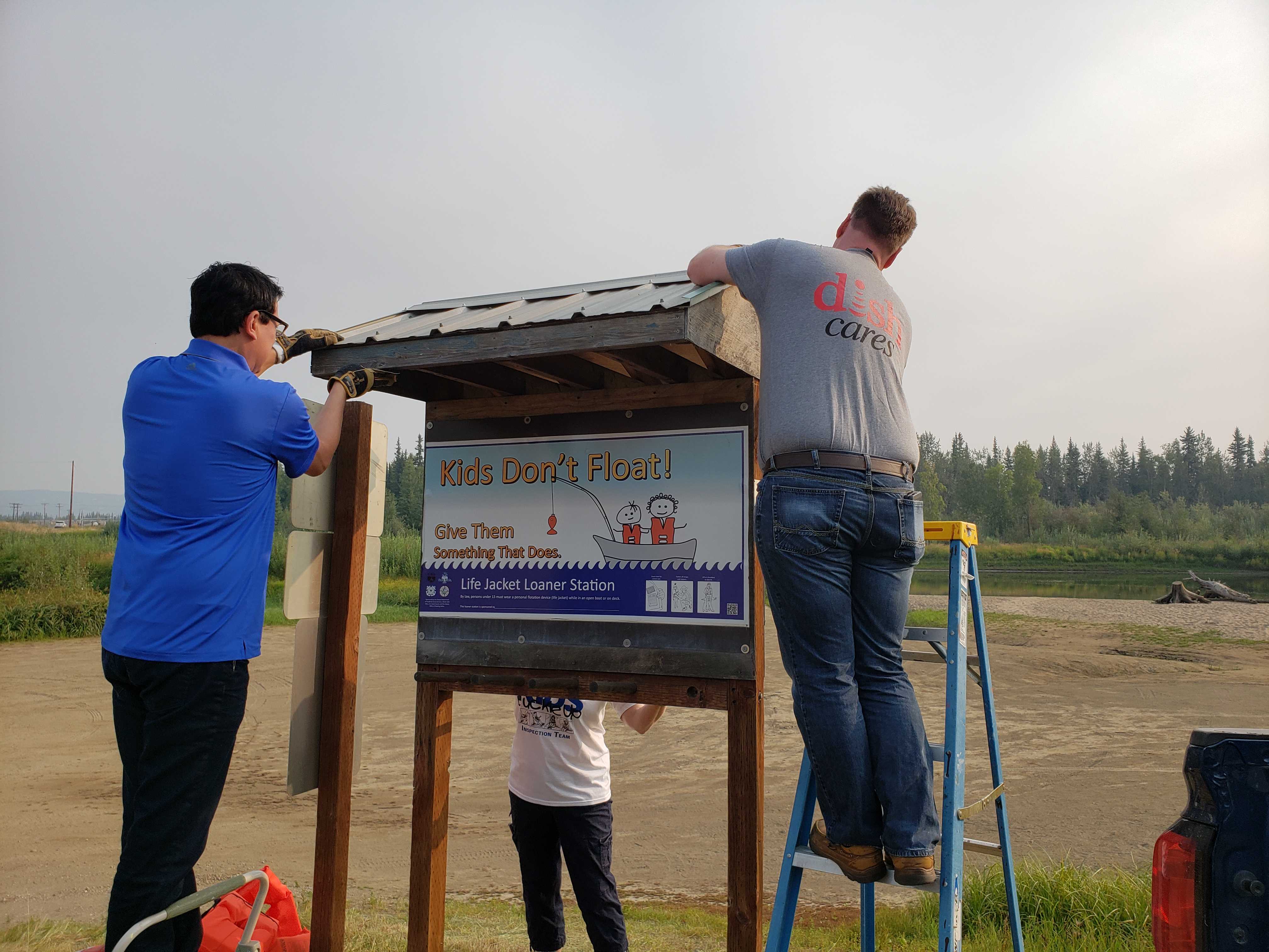 Microcom employees installing a Kids don't float life jacket loaner board