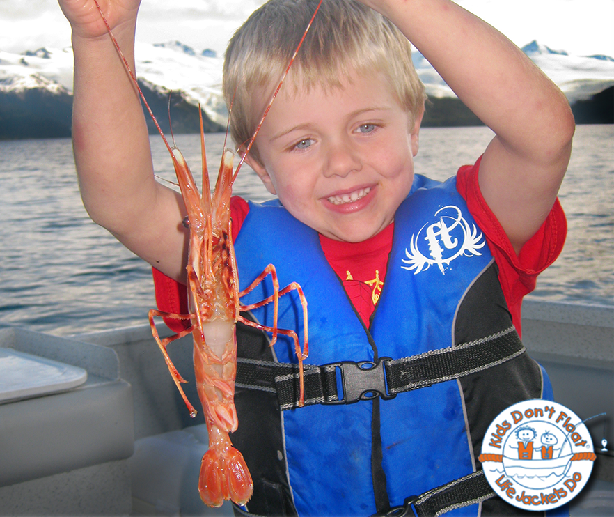 child holding up large shrimp by the antennae with Kids Don't Float logo in bottom right corner