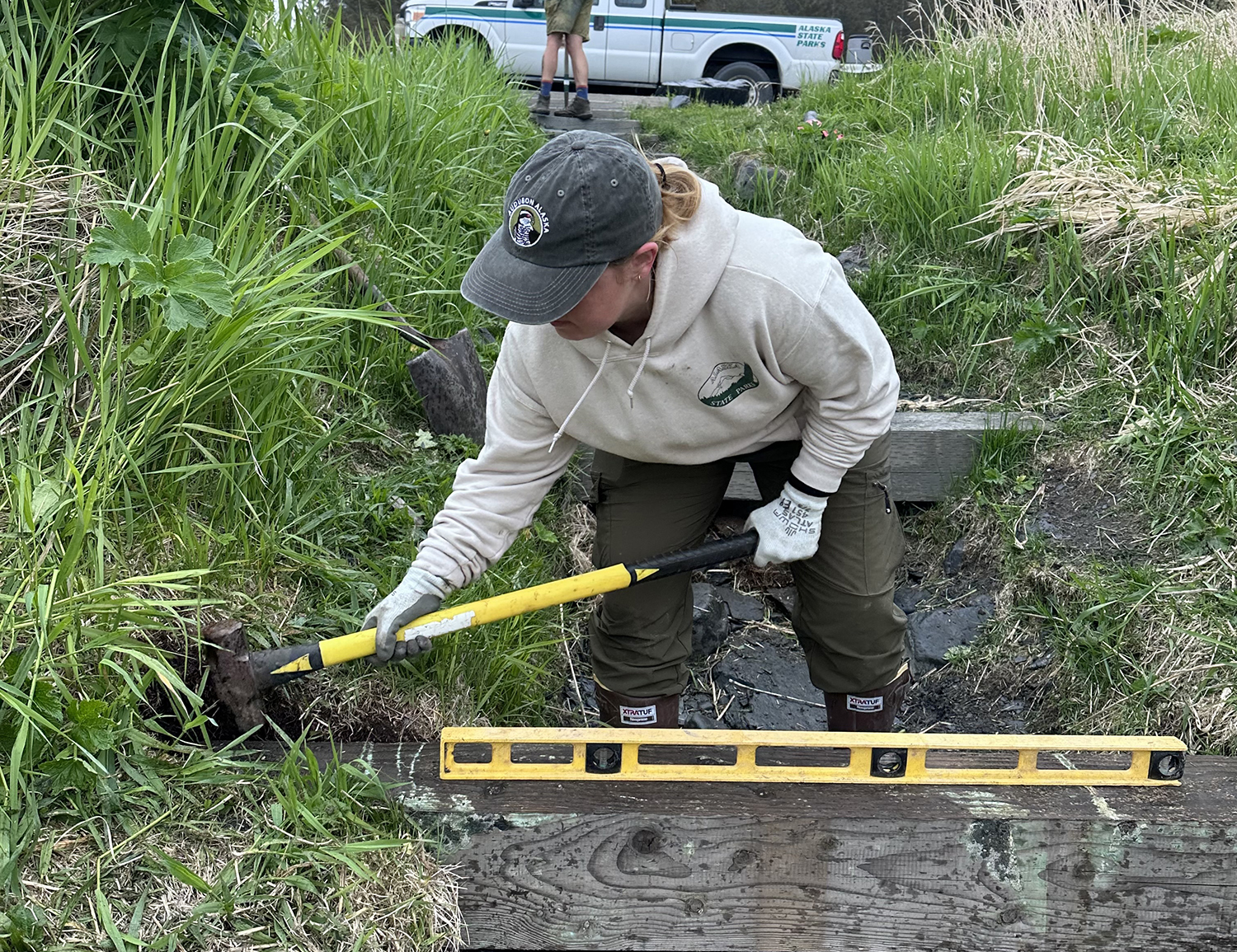 ACC using a sledge hammer to level out a wooden trail step