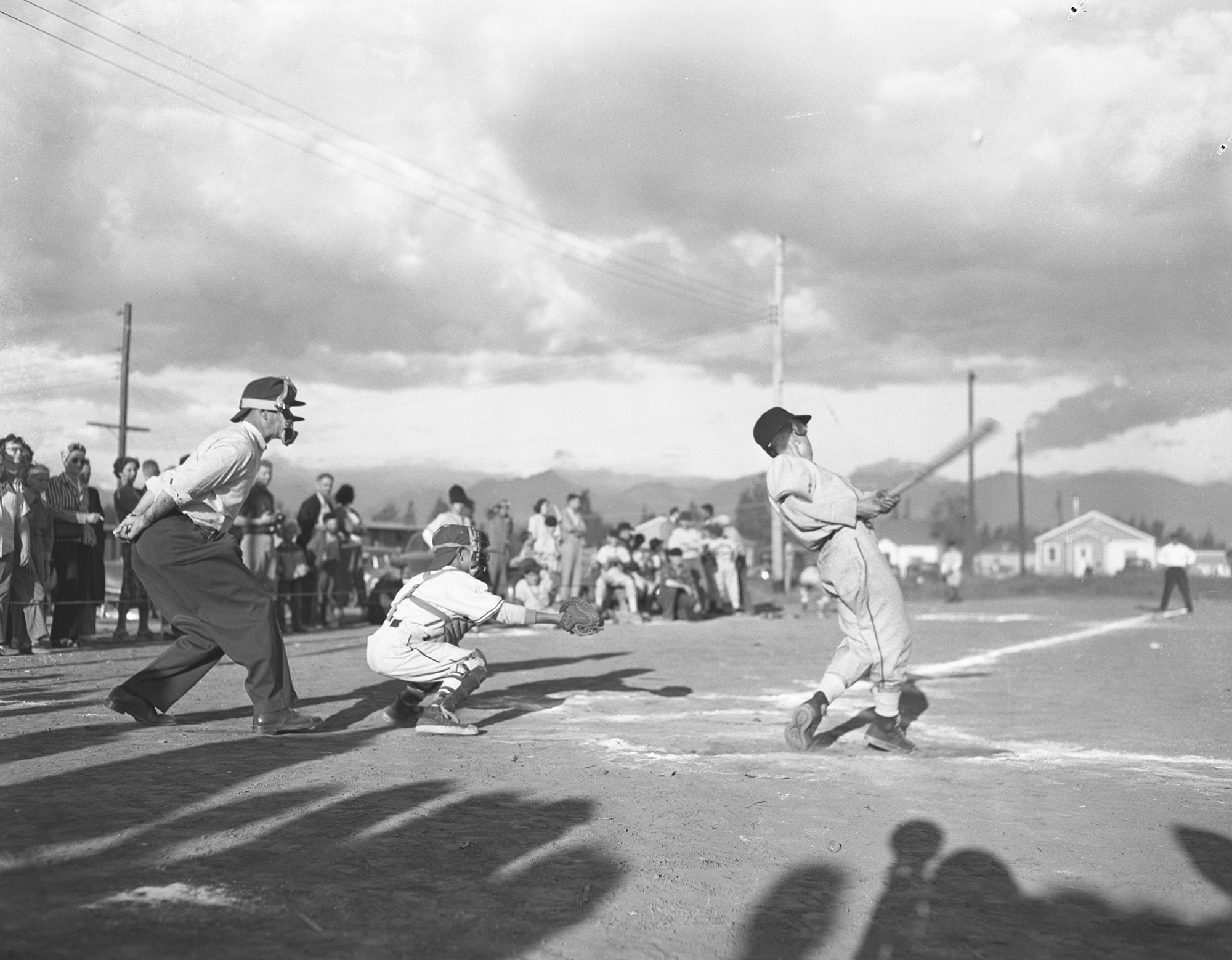 black and white photo of baseball game, batter swinging and hitting ball