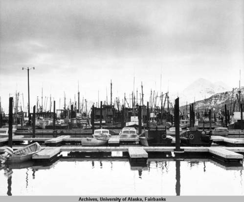 A black-and-white photo of Kodiak Harbor circa 1960's, taken shortly before the 1964 Earthquake. Im-age courtesy of University of Alaska Fairbanks, Alaska and Polar Regions Collections, Alaska Earthquake Archives Committee Collection, UAF-1972-153-52.