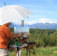 man painting portrait of Mount Denali outside